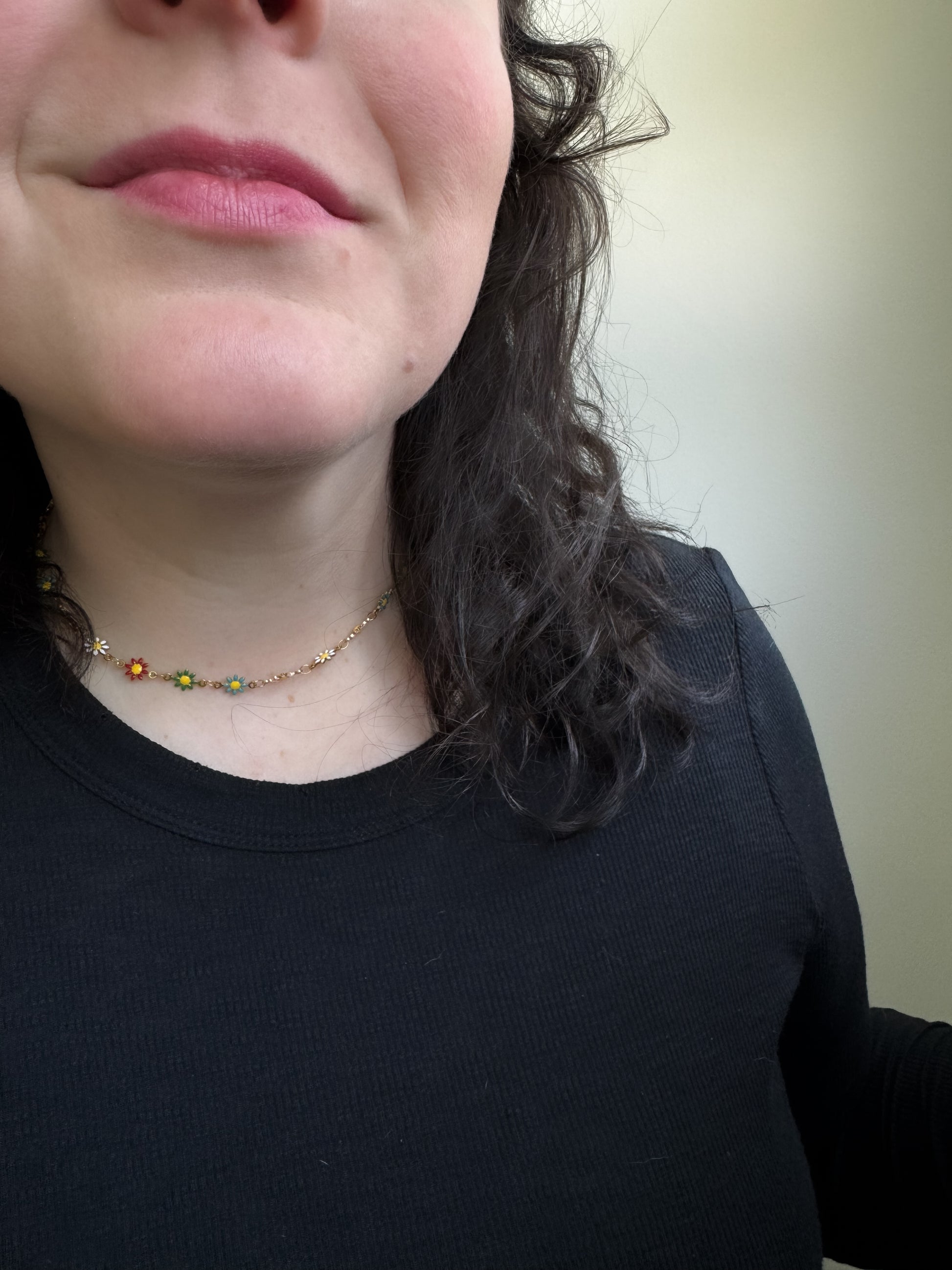 Close-up of a person wearing a black shirt and a necklace with small beads.