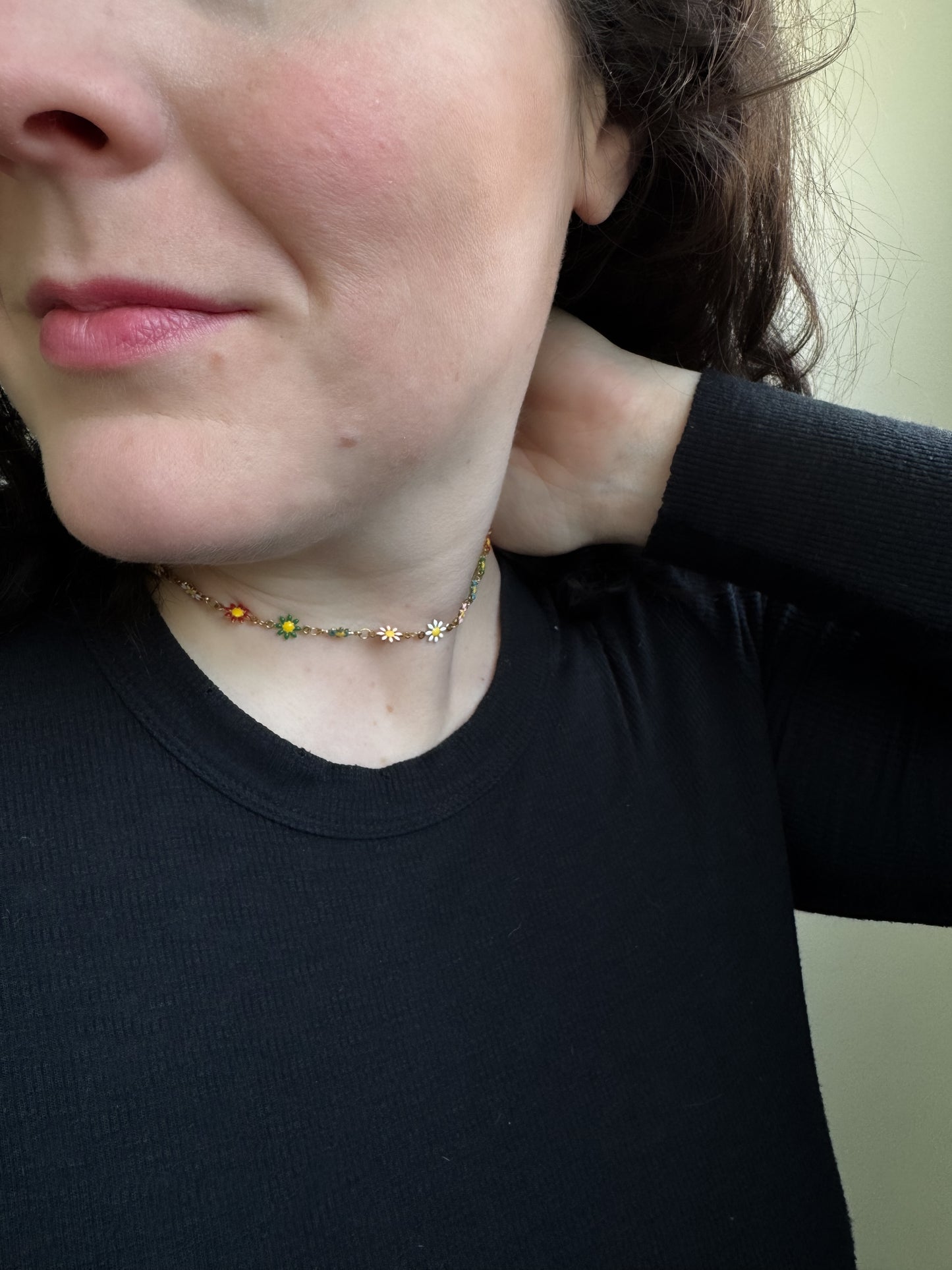 Person wearing a black shirt with a necklace featuring sunflower pendants.