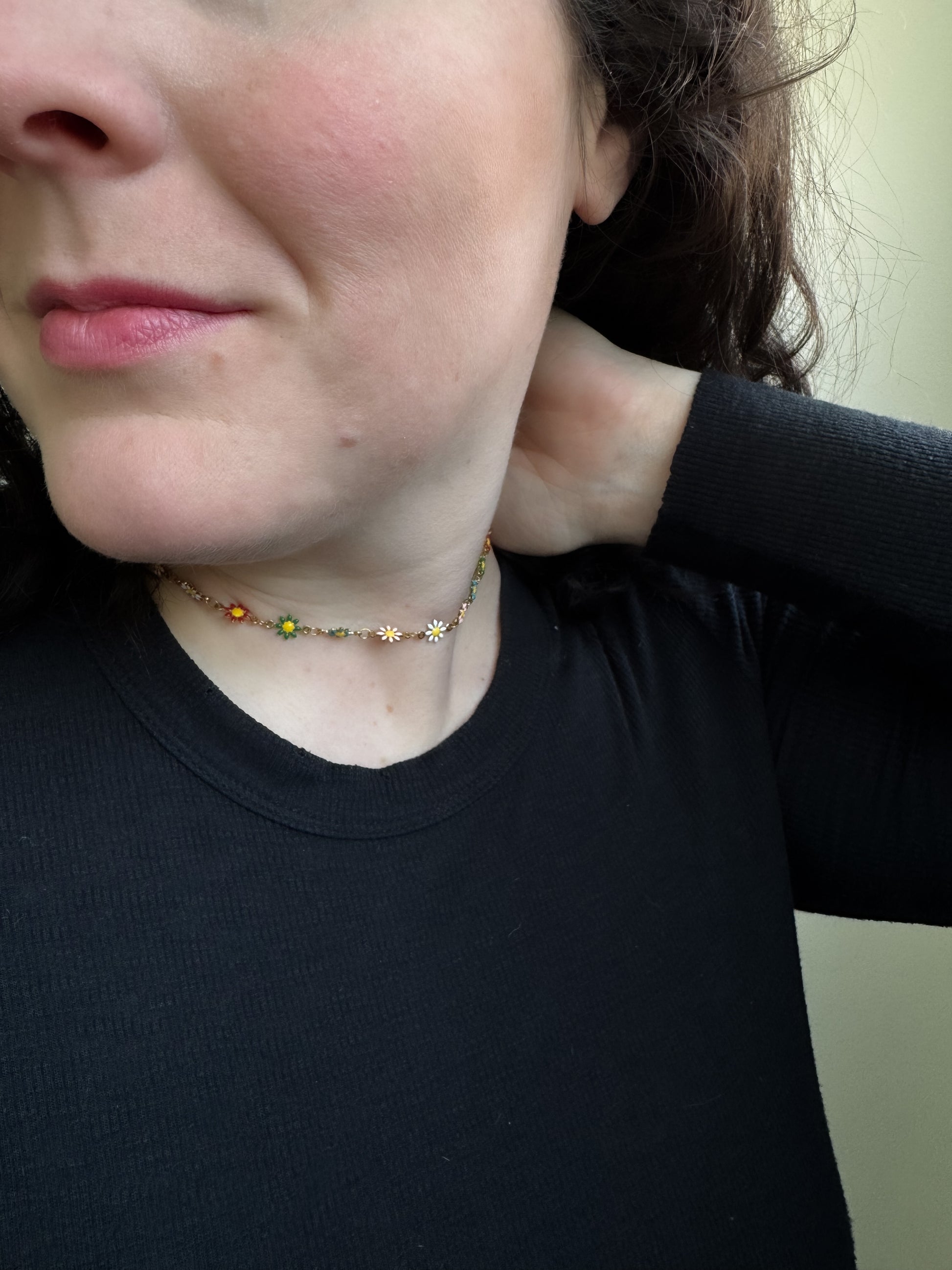 Person wearing a black shirt with a necklace featuring sunflower pendants.