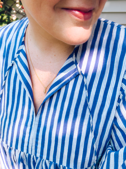 Close-up of a person wearing a blue and white striped shirt with a necklace.