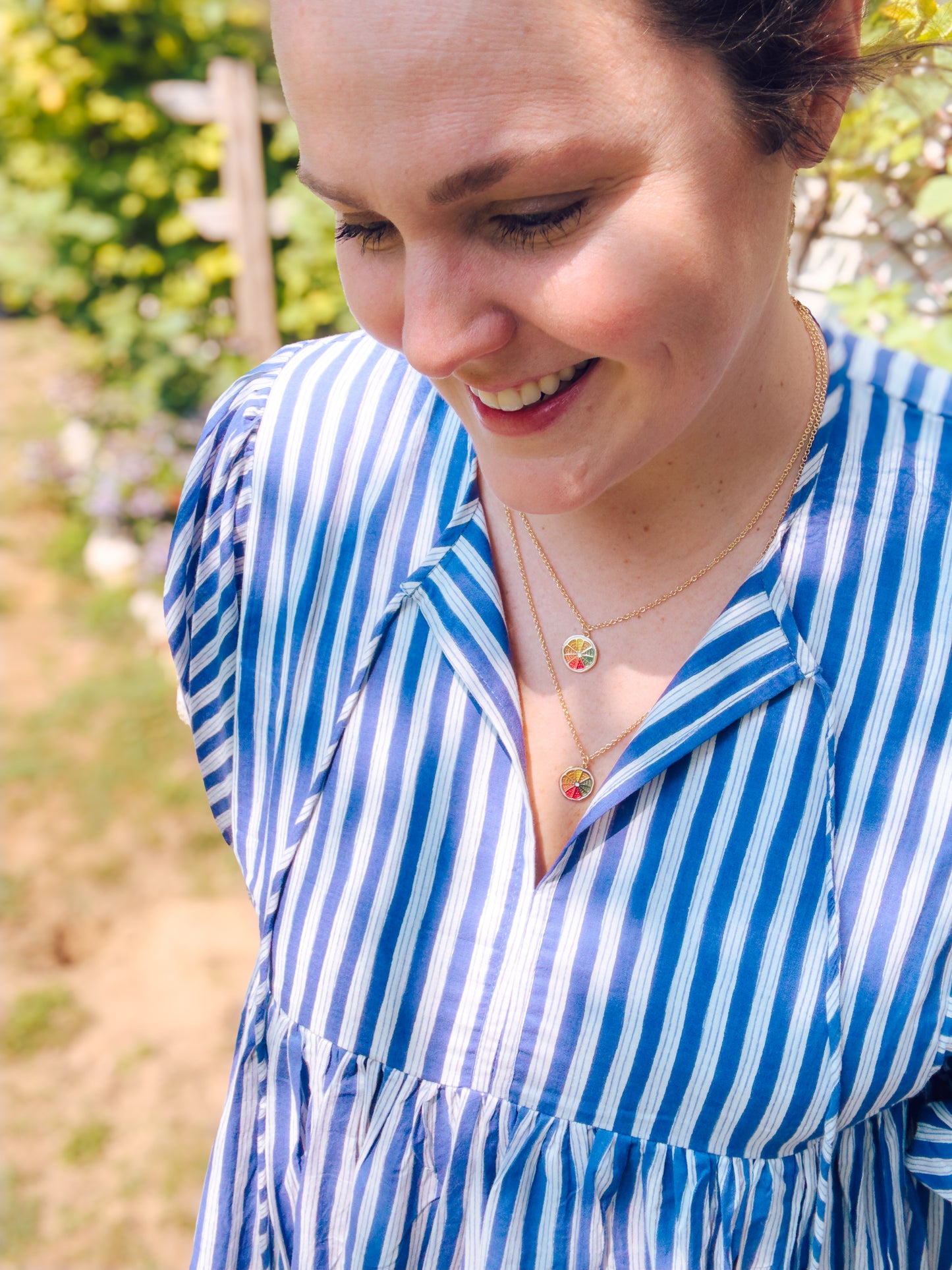 Woman wearing a blue and white striped shirt with a blurred outdoor background