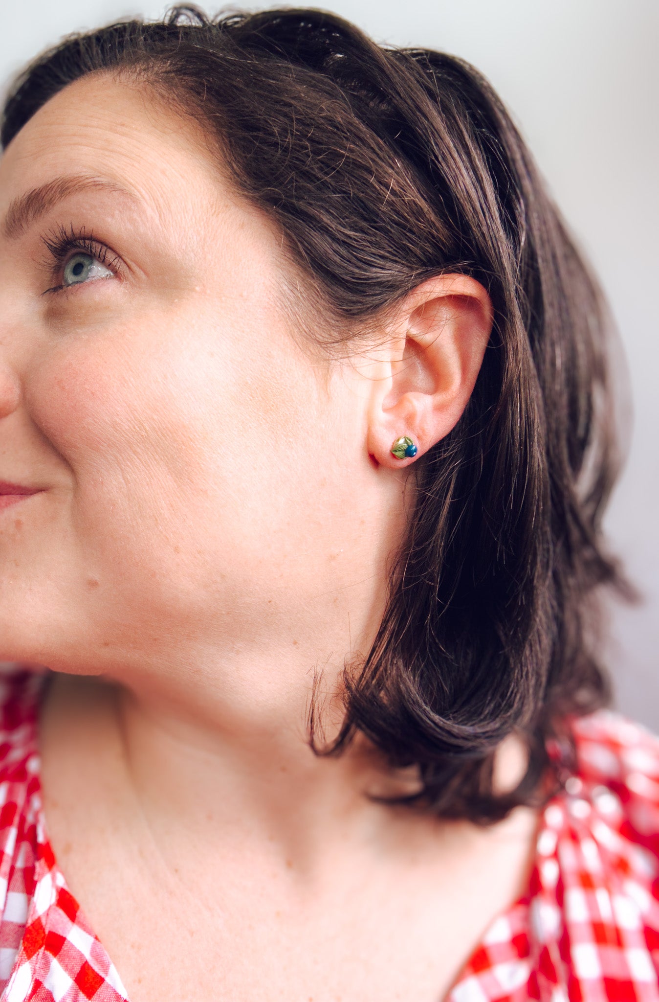 Close-up of a person wearing earrings with a neutral background