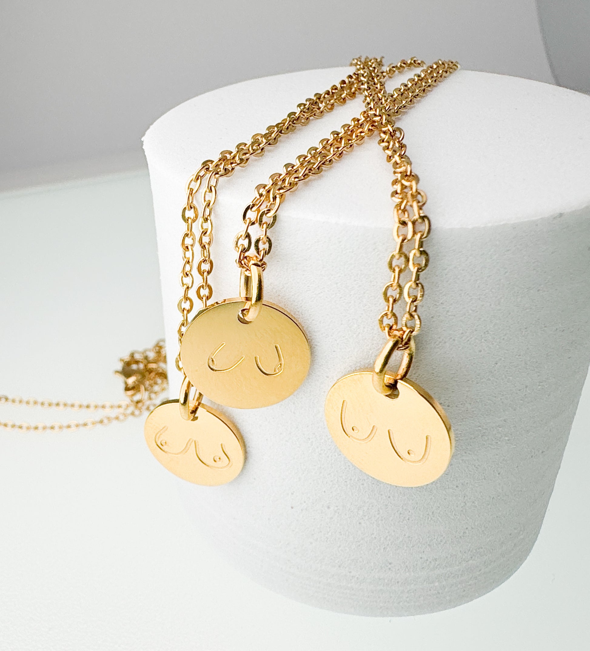 Gold necklaces with round pendants on a white stand