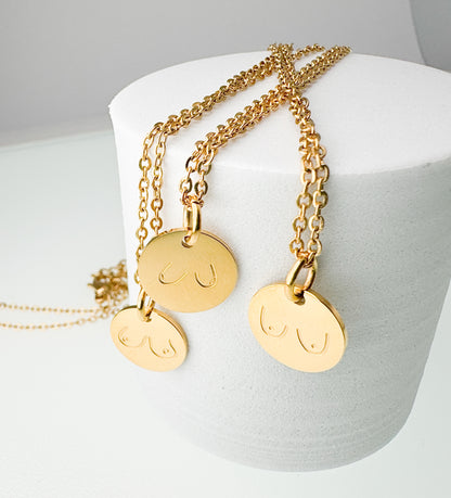 Gold necklaces with round pendants on a white stand