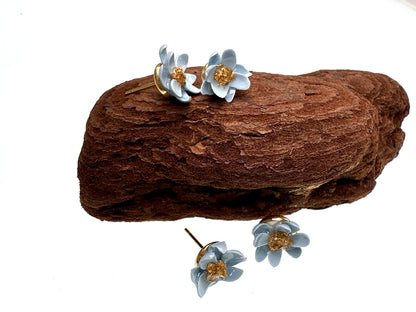 Floral earrings on a piece of brown wood with a white background
