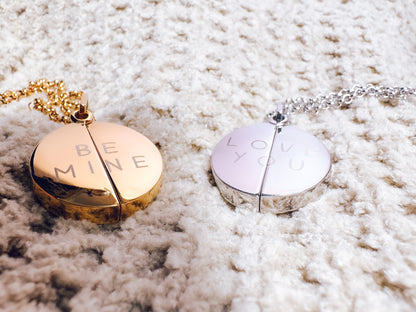 Two heart-shaped necklaces with 'BEE MINE' and 'LOVE YOU' on a textured surface.