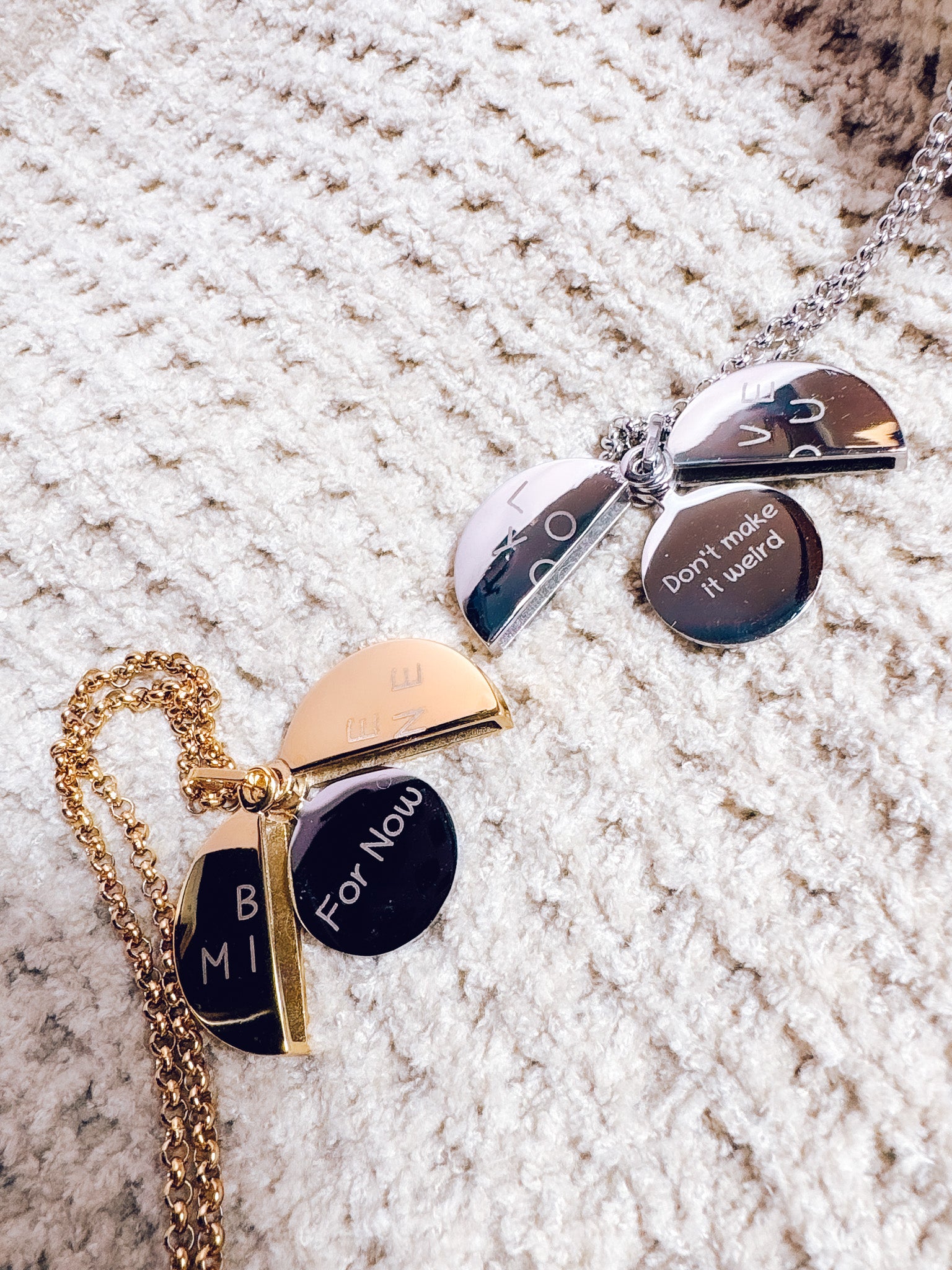 Two necklaces with engraved pendants on a textured surface