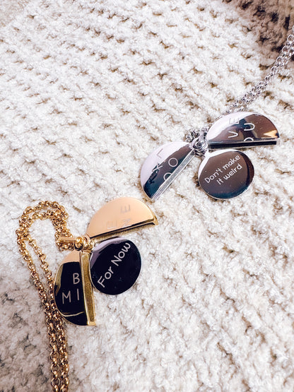 Two necklaces with engraved pendants on a textured surface