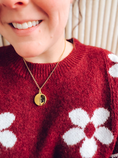 Person wearing a red sweater with white floral patterns and a gold necklace.