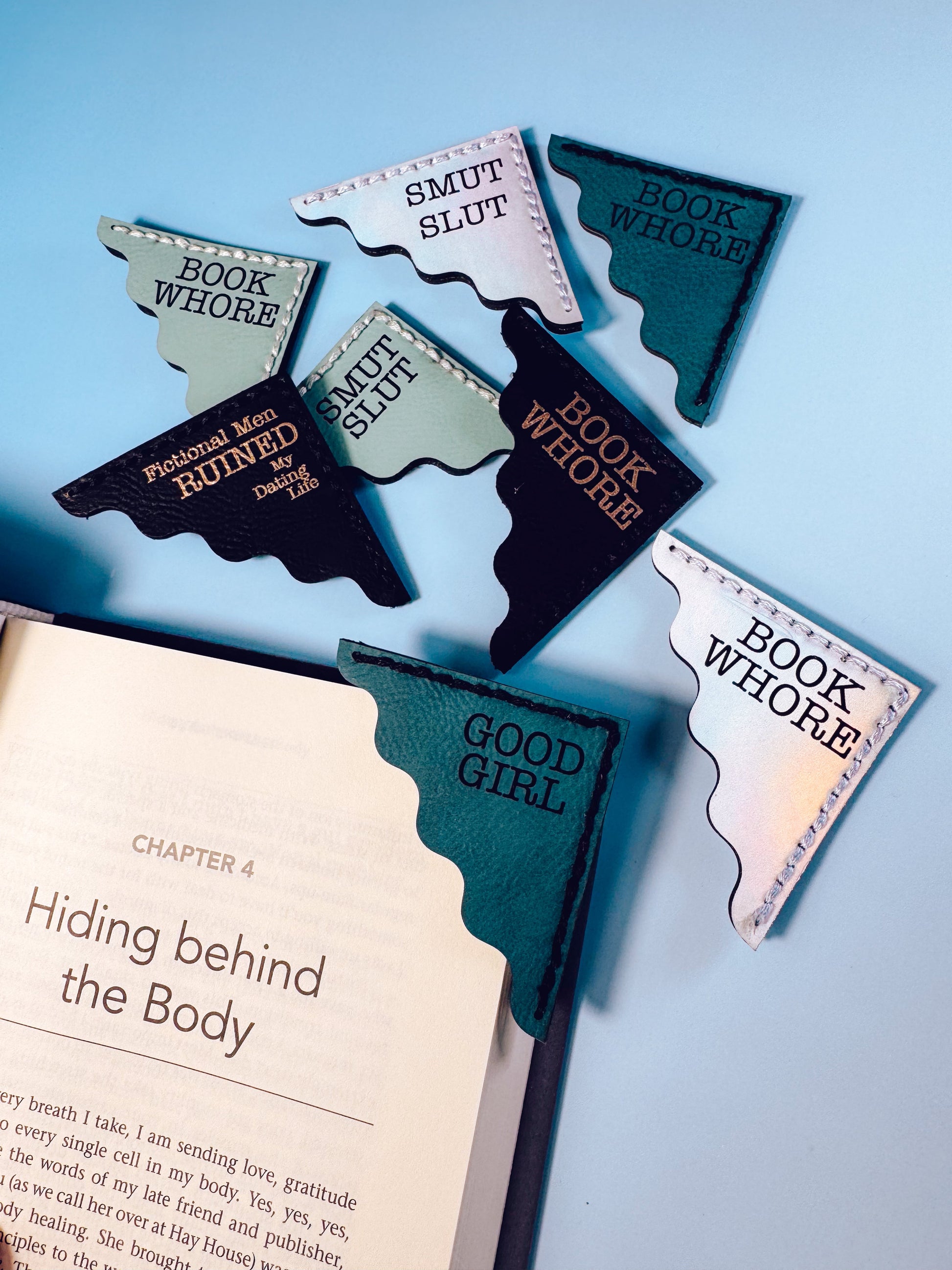 Bookmarks shaped like state outlines with humorous text on a book and blue background