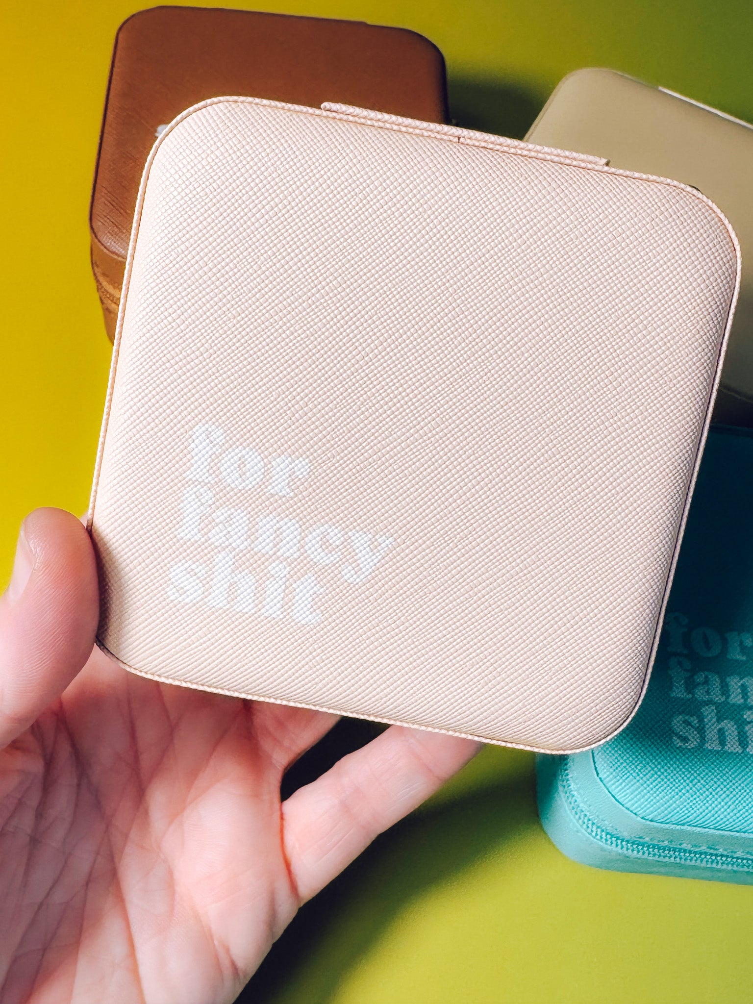 Beige pouch held in a hand with text 'for fancy shit' on a yellow background