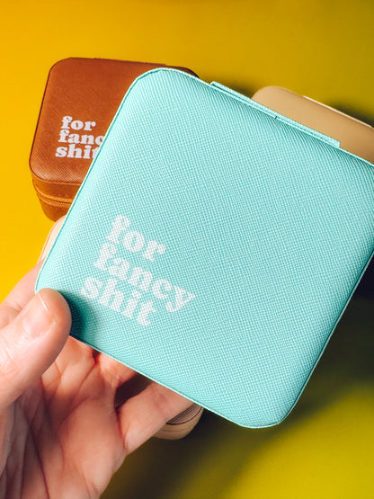 Turquoise wallet with 'for fancy shit' text held by a hand against a yellow background