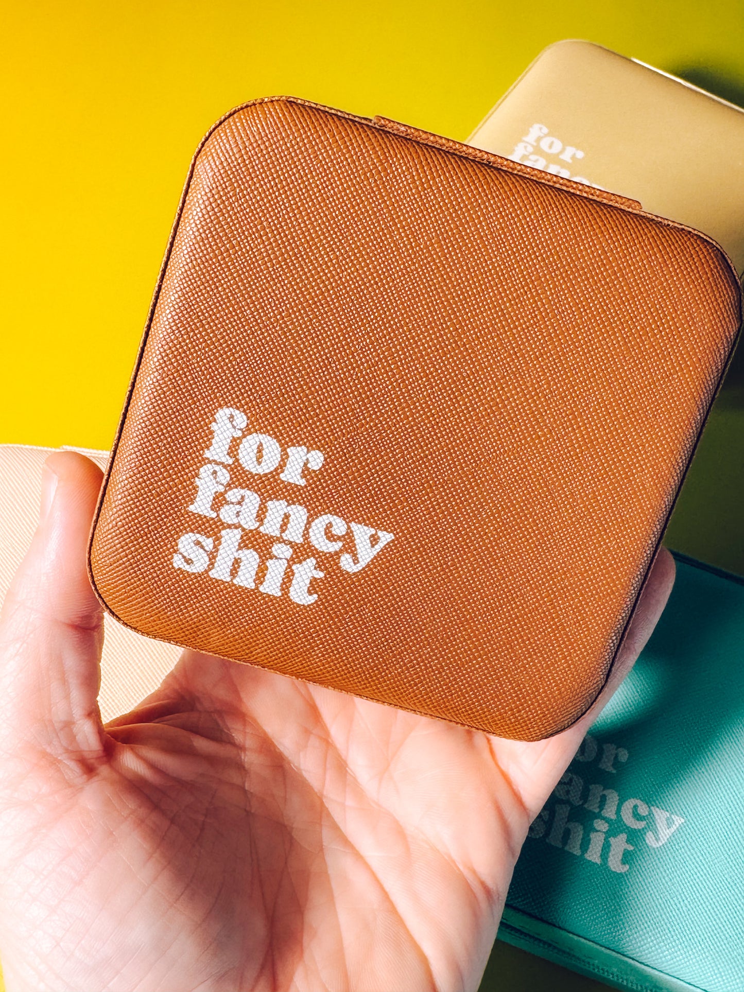 Brown pouch with 'for fancy shit' text held by a hand against a yellow background