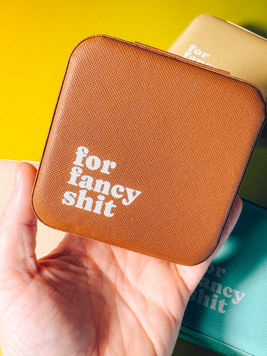 Brown pouch with 'for fancy shit' text held by a hand against a yellow background