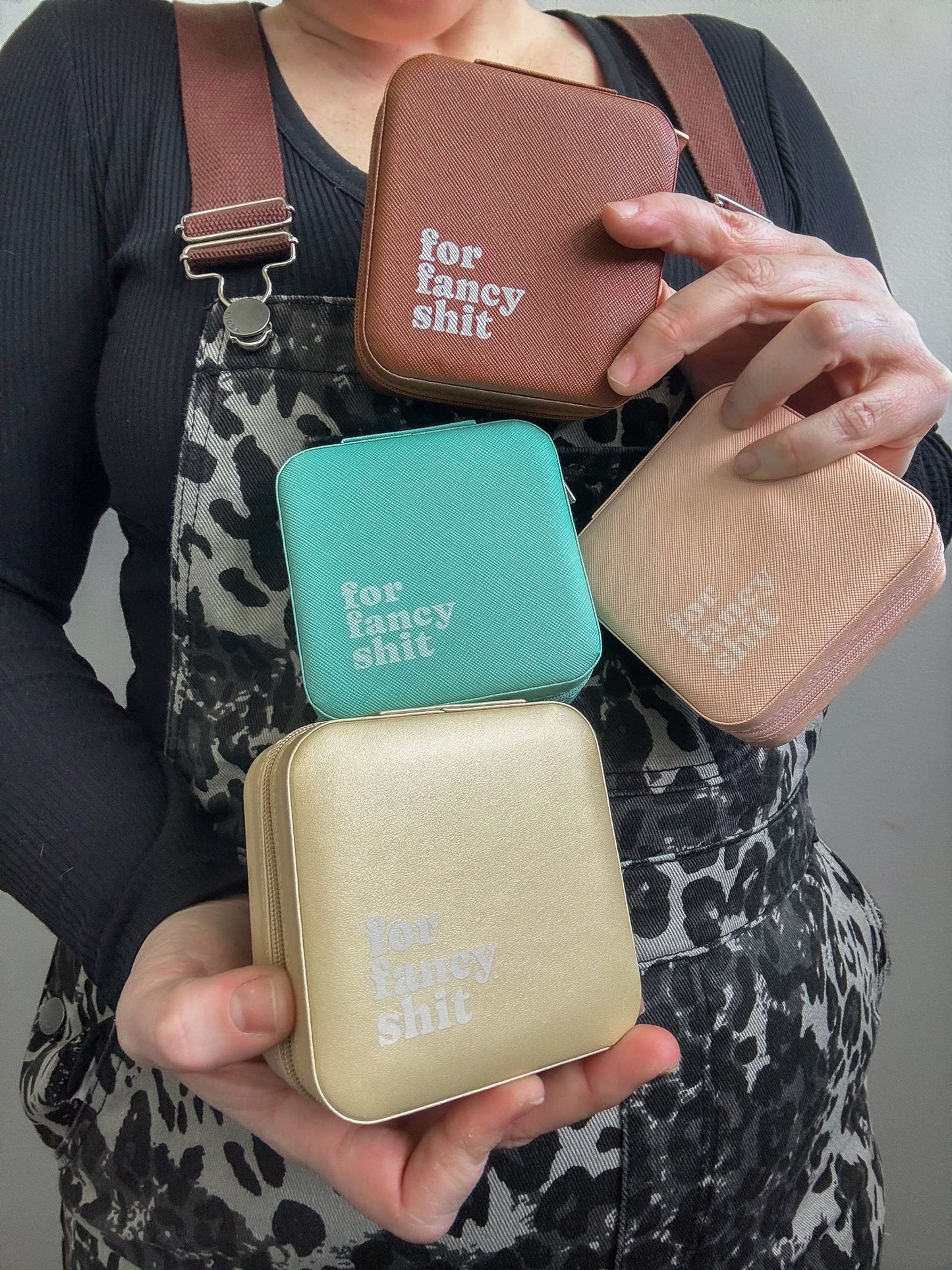Person holding four small rectangular bags with text 'for fancy shit' on a neutral background