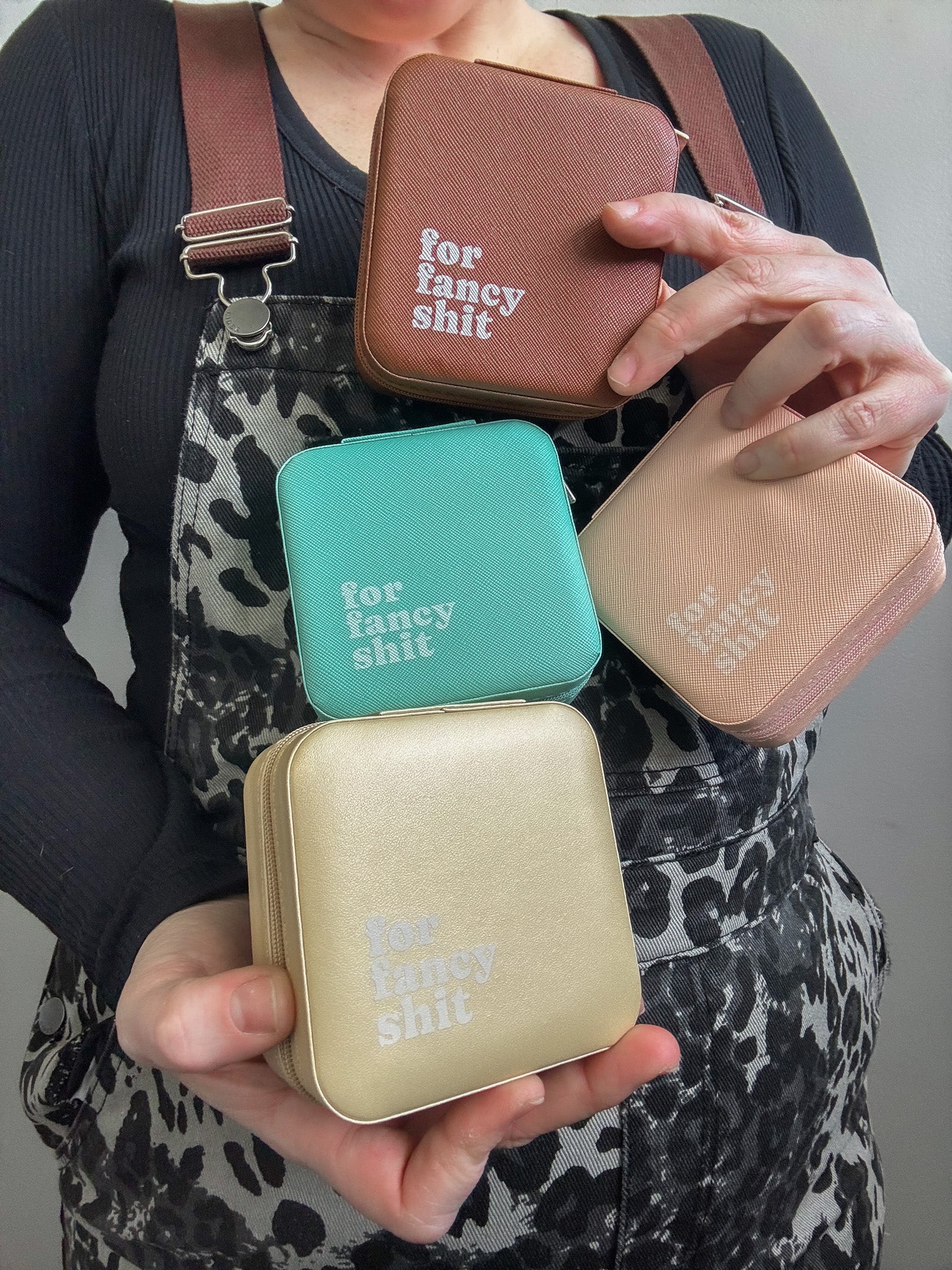 Person holding four small rectangular bags with text 'for fancy shit' on a neutral background